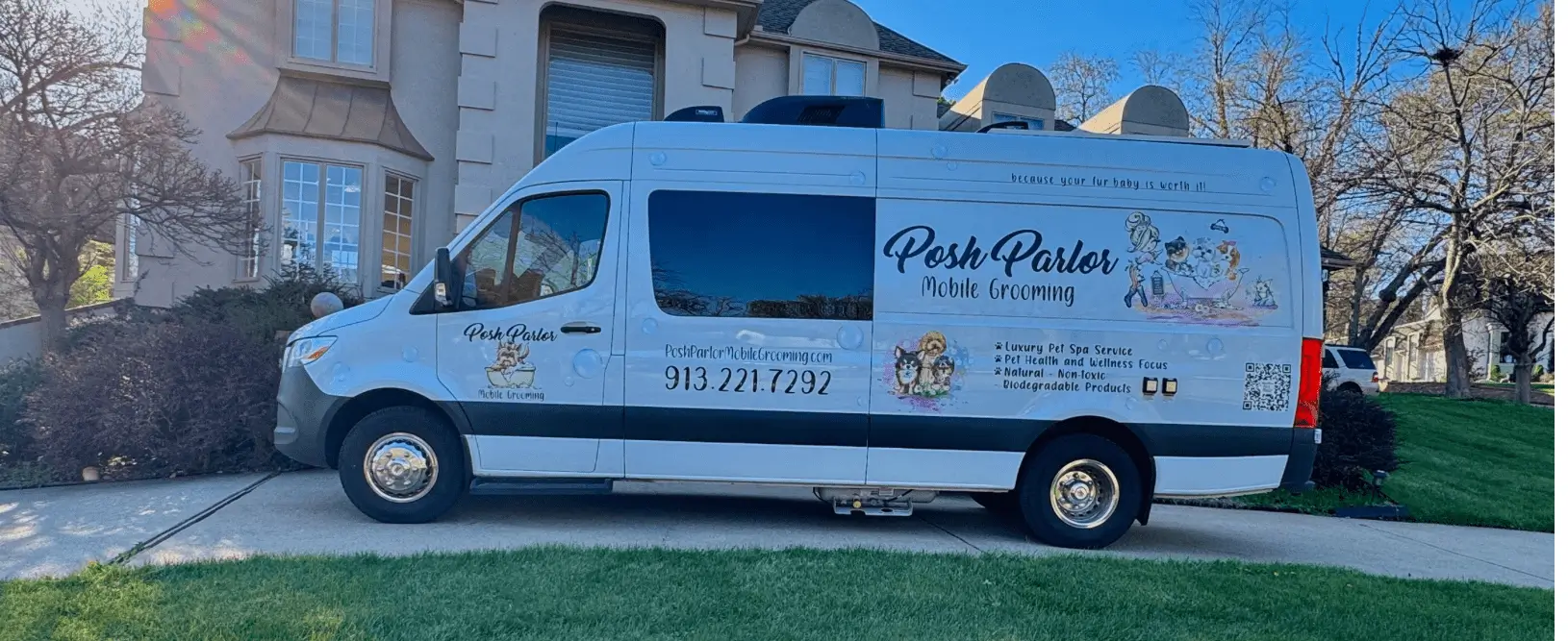 Mobile pet grooming van parked outside house.